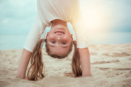 Familienurlaub am Strand - Kind macht Handstand im Sand.
